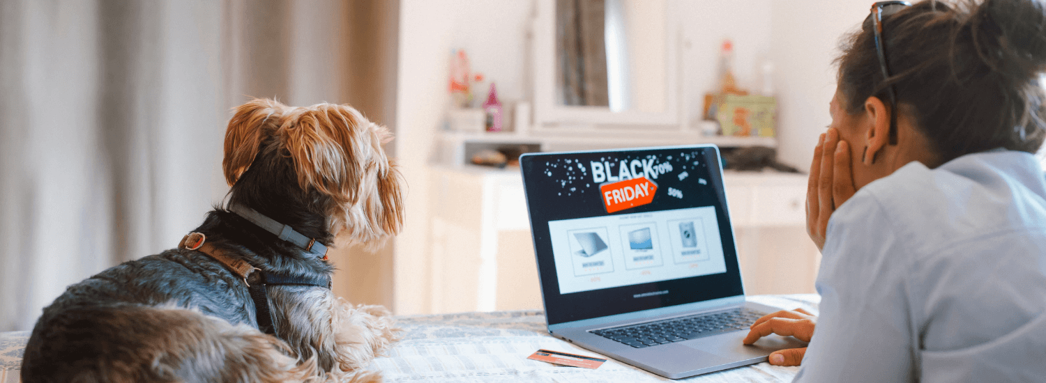 Young woman online shopping on her laptop with her dog sitting beside her